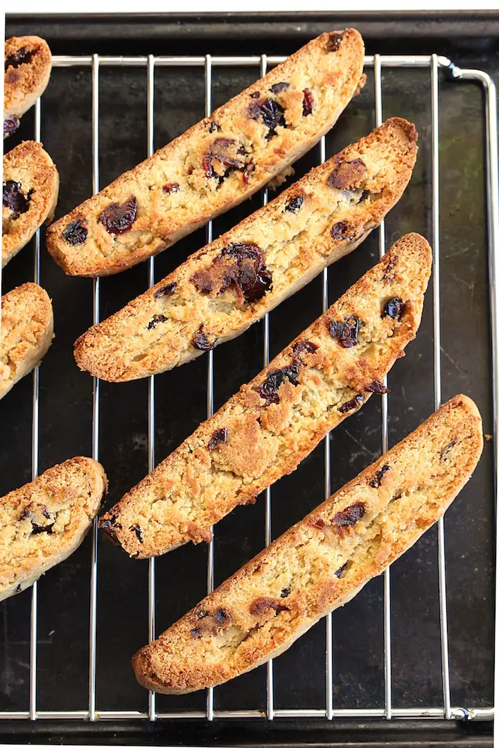 Gluten-Free Orange Cranberry Biscotti cut side up on a cooling rack that is on a baking sheet.