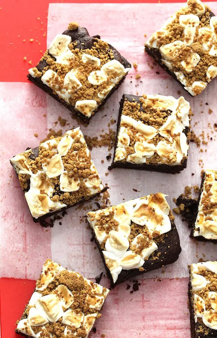 Squares of Vegan Gluten-Free S'mores Brownies arranged on a red cutting board