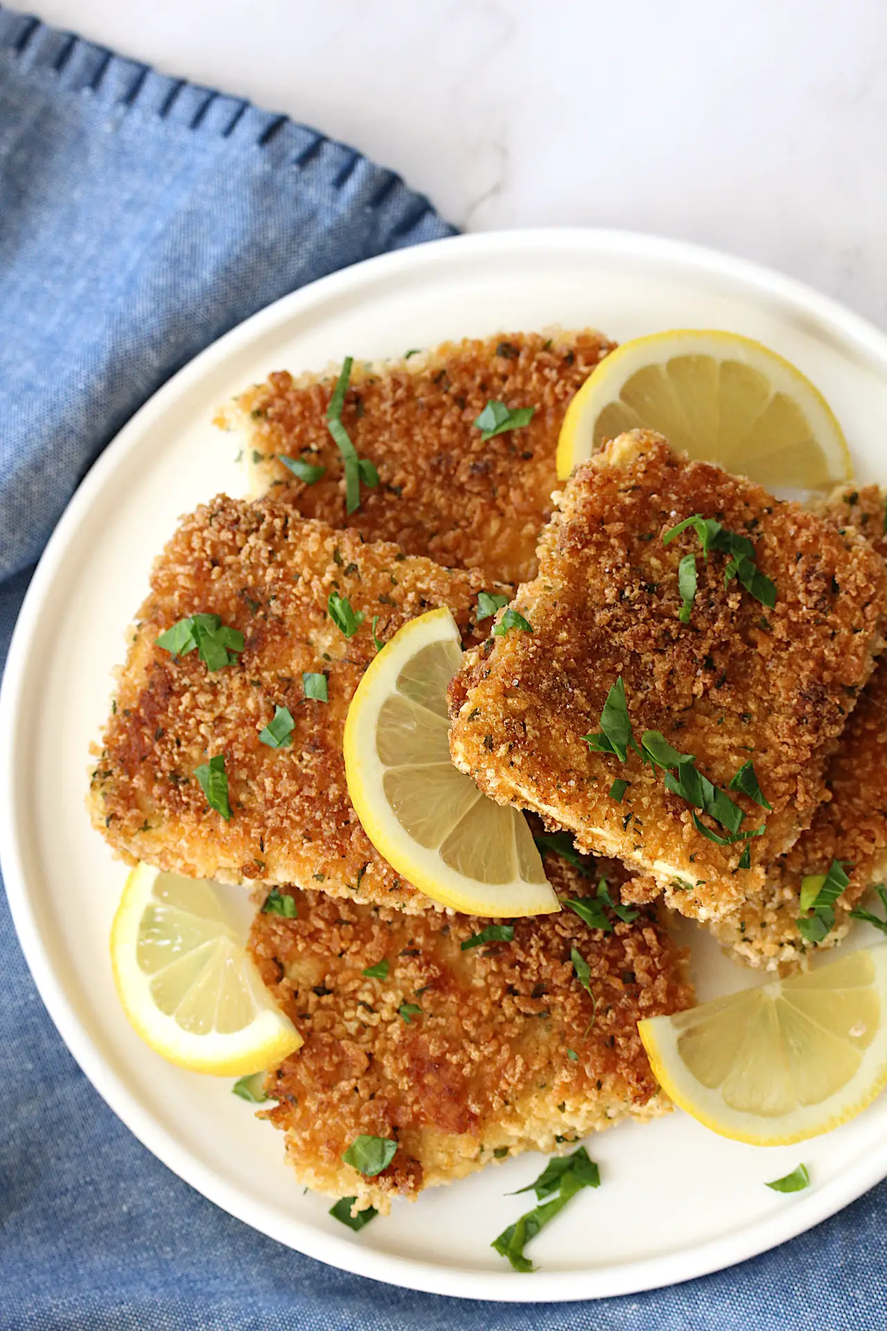Vegan gluten-free tofu schnitzel on a plate with parsley and slices of lemon