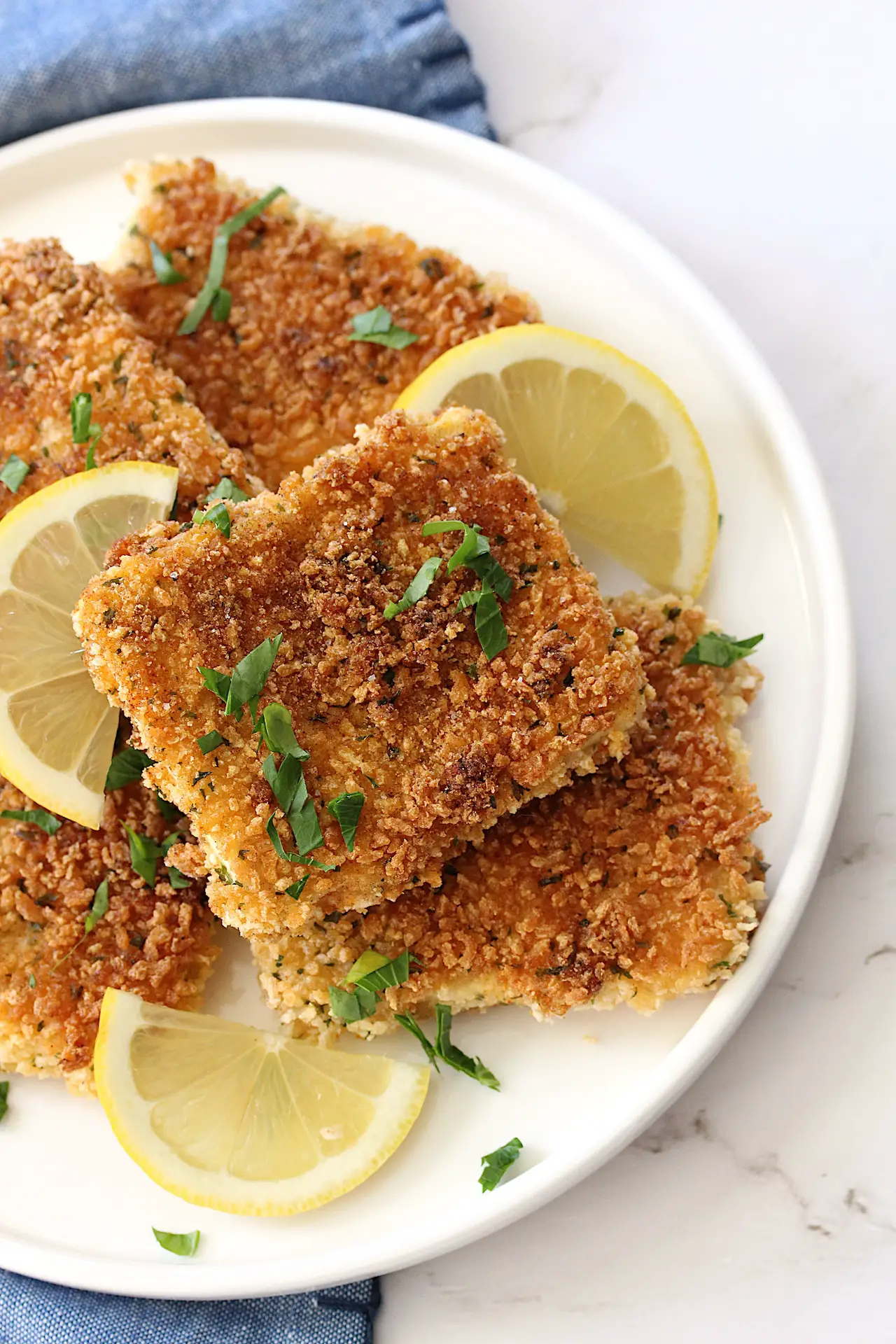 Vegan gluten-free tofu schnitzel on a plate with parsley and slices of lemon