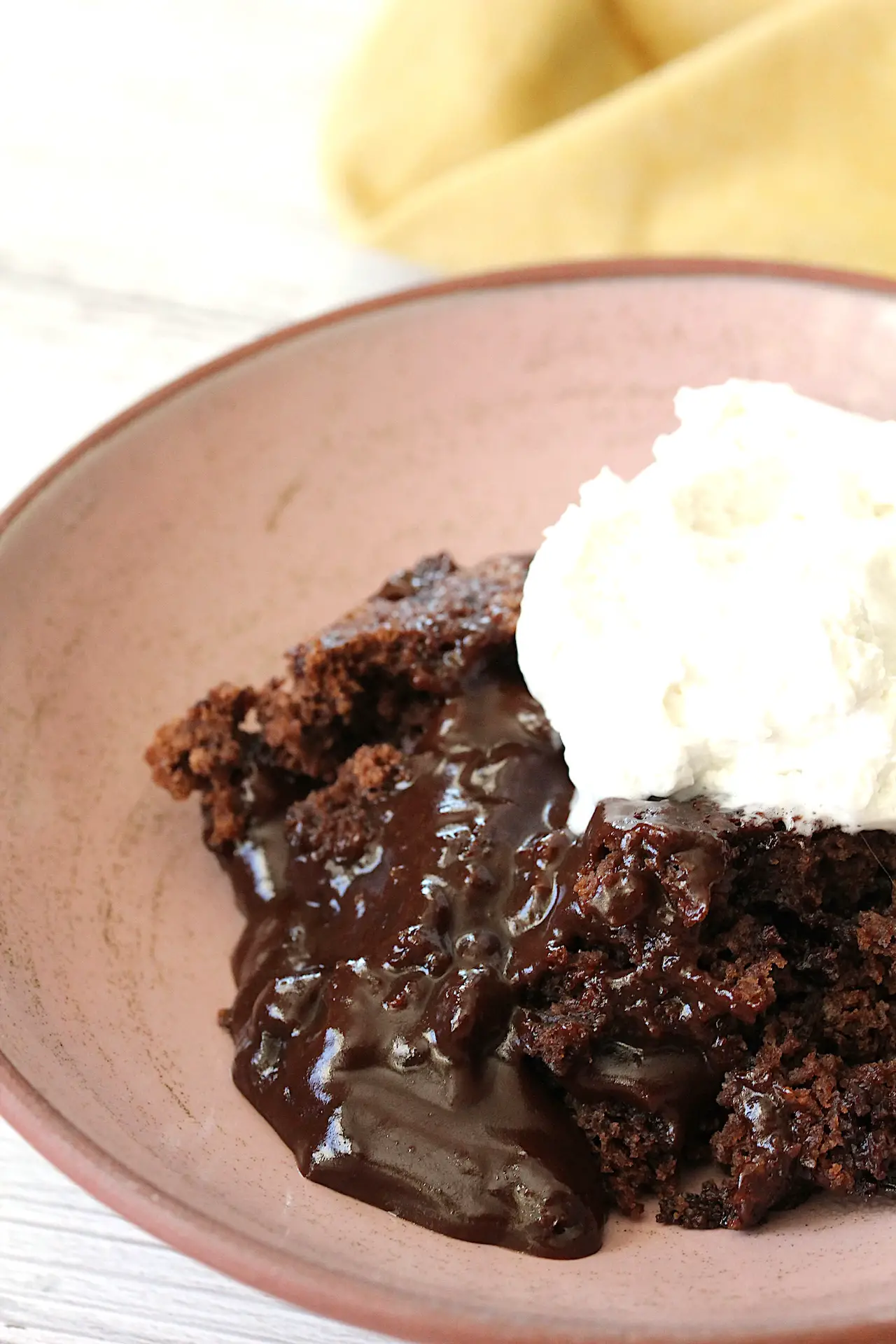 chocolate pudding cake in a bowl with some coconut whip on top