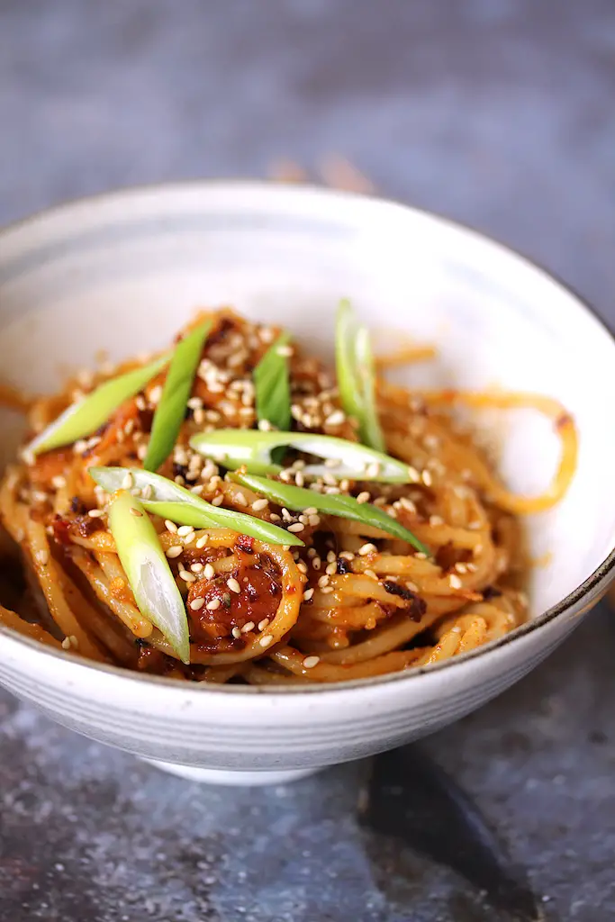Close up image of this 1-serving chili crisp noodles in a bowl with chopsticks to the side.