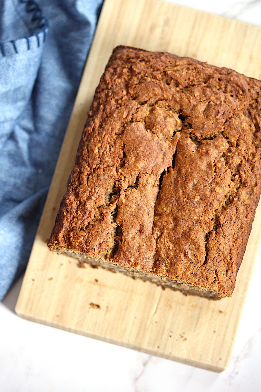 Loaf of Coconut Carrot Banana Bread on a cutting board with a blue napkin in the background